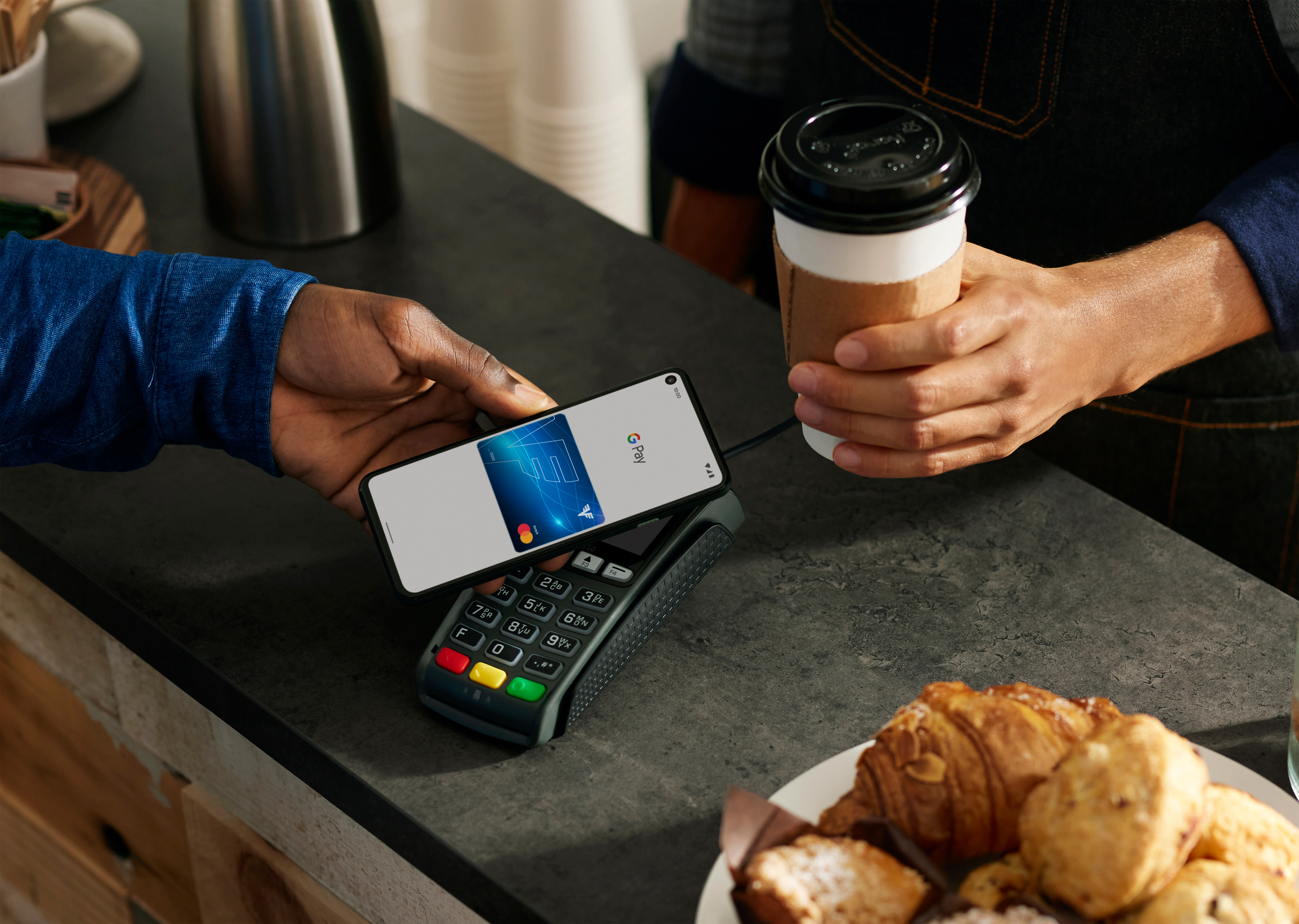In einem Café verwendet ein Mann Google Pay auf seinem Smartphone zum bezahlen.