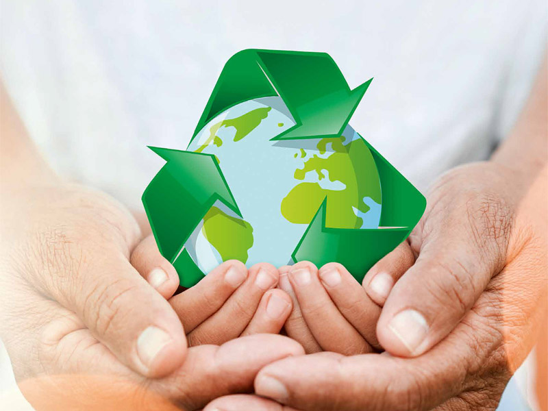 In den Händen einer Person schebt die graphische Darstellung der Erde umgeben von grünen Recycling-Pfeilen.